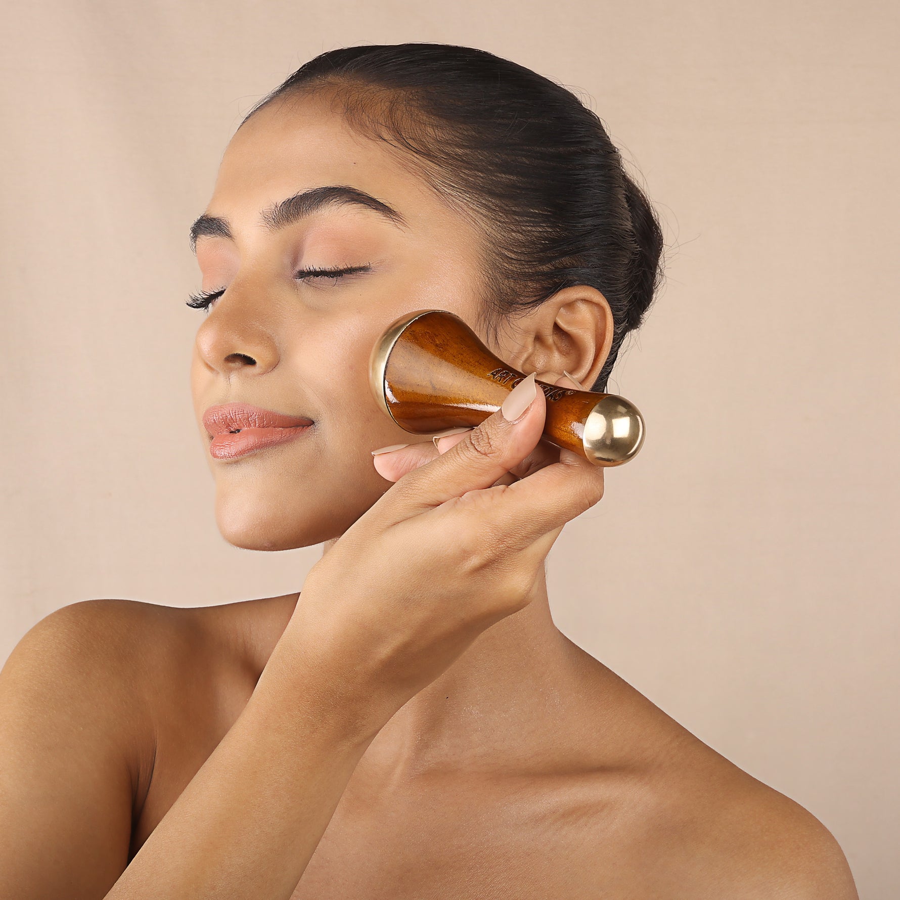 Woman using Art of Vedas Kansa wand for Ayurvedic facial massage - bronze and wood face massage tool for skin rejuvenation and Marma therapy